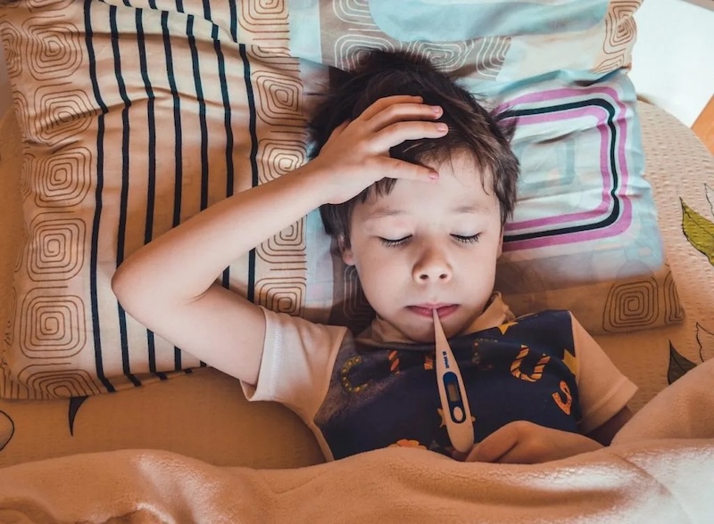 Sick Boy with thermometer in bed
