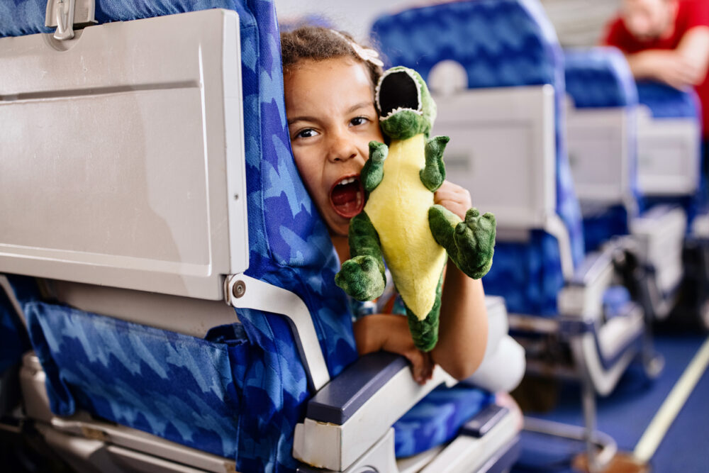 Little girl playing with plush toys while traveling by plane