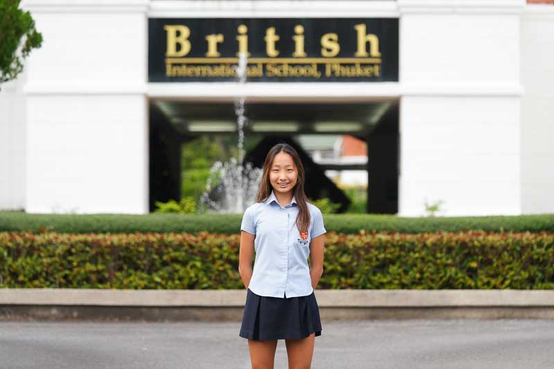 BISP - student standing in front of school